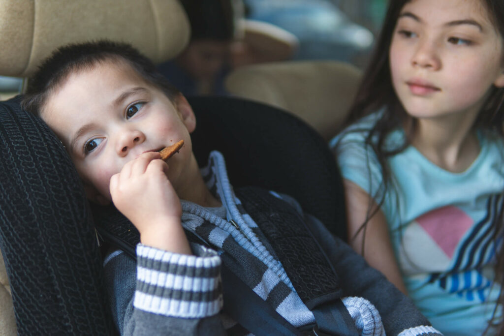 child looking out window in car with sister