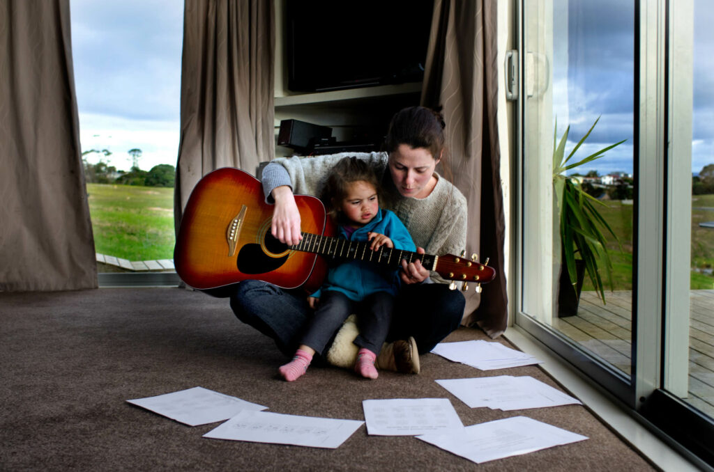 Mother and child sitting together, playing guitar.